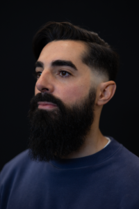 Photo d'un homme brun avec une coupe rétro dégradée à blanc et une longue barbe foncée bien taillée